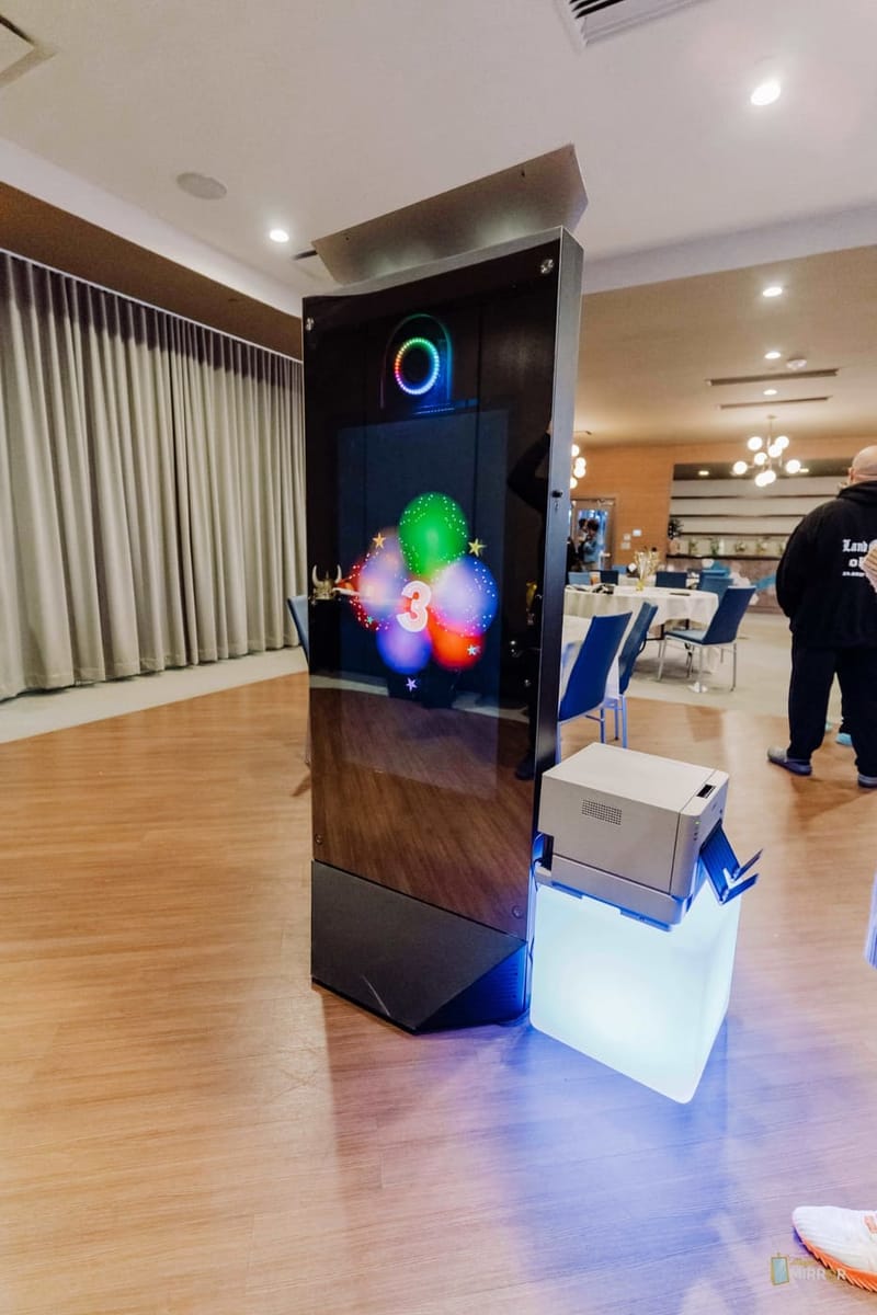 Mirror X booth mid-countdown with its instant printer on an LED plinth