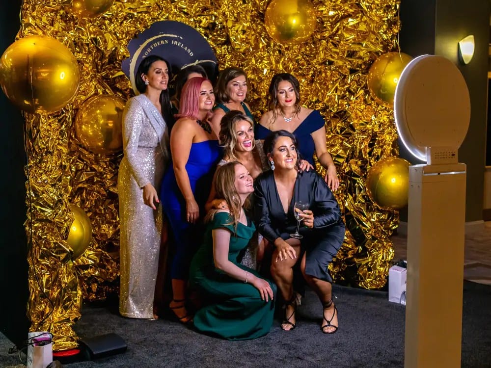 Guests posing for the studio booth in front of a gold sequin wall at a New Jersey gala