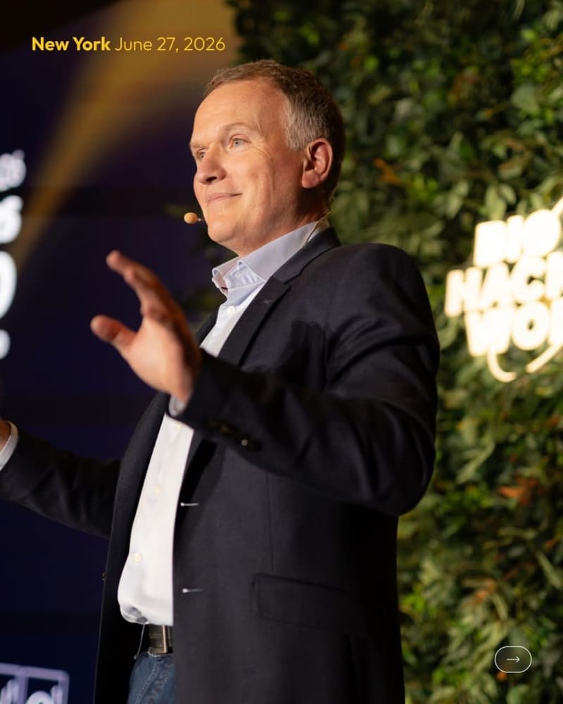 Speaker mid-talk in front of a lit greenery wall