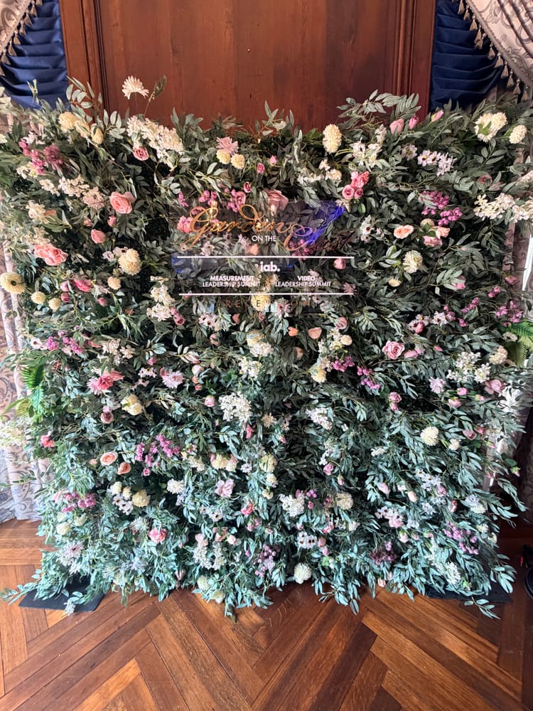 Pastel garden wall of eucalyptus, roses and blossom with a gold acrylic sign