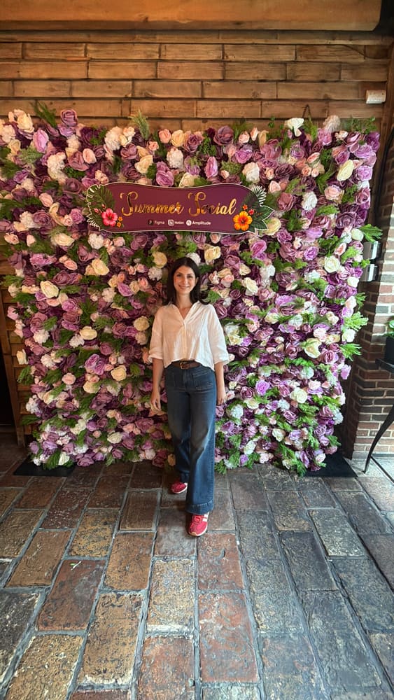 Guest posing at a mauve and blush rose wall with a Summer Social sign, brick venue