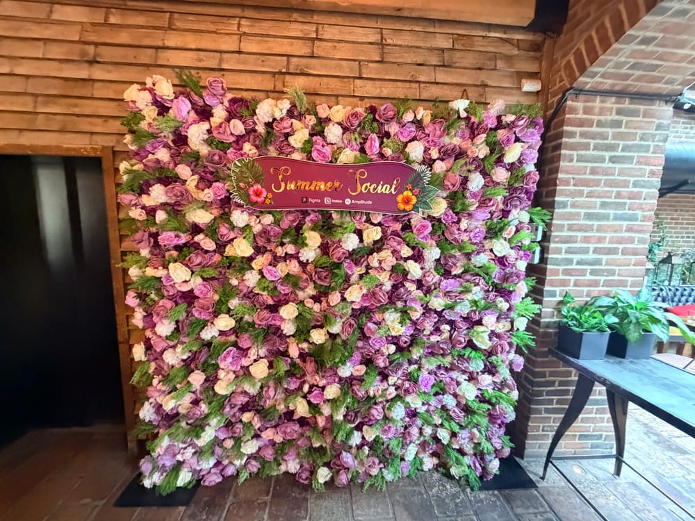 Mauve and blush rose wall with a burgundy Summer Social sign in a brick venue