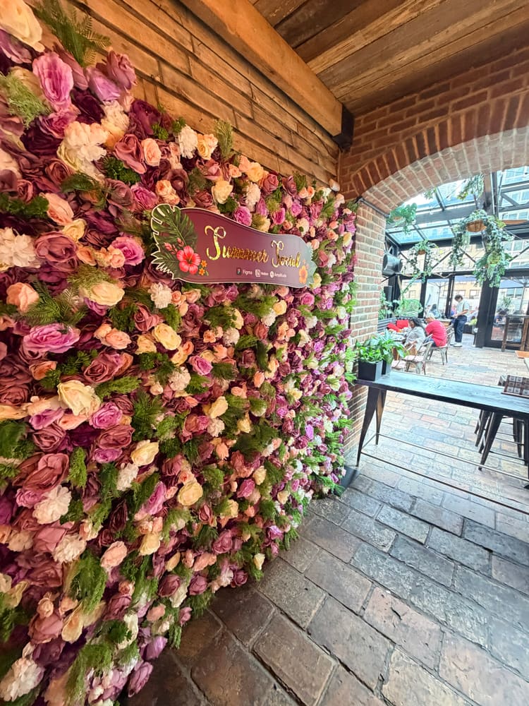 Angled view of a blush and mauve rose wall in a brick-arched venue
