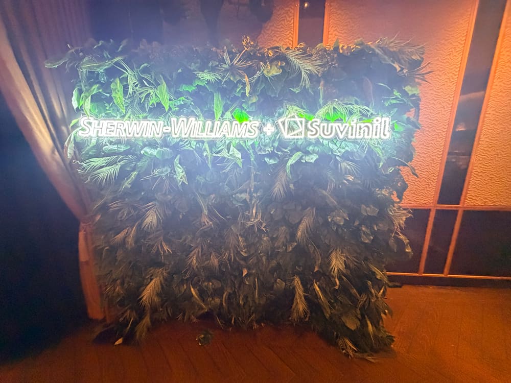 Brand-lit greenery wall glowing in a darkened event room
