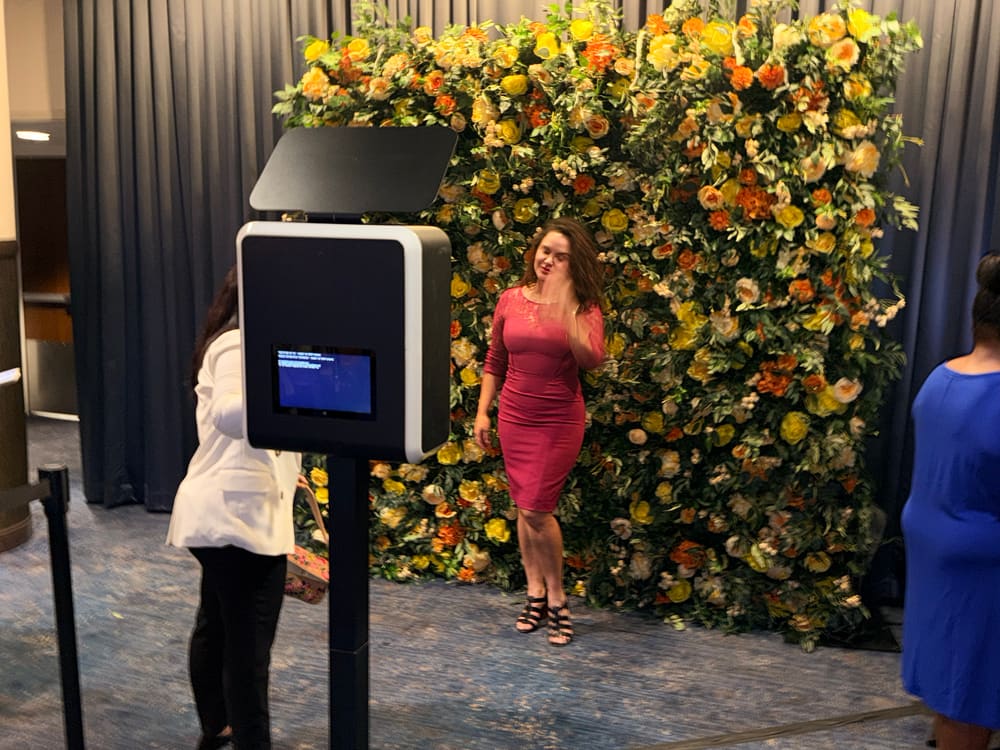 Guest in a red dress photographed at a yellow and orange rose wall