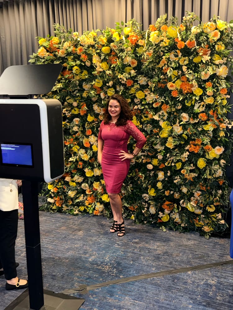 Guest posing at a citrus rose wall while the booth attendant works