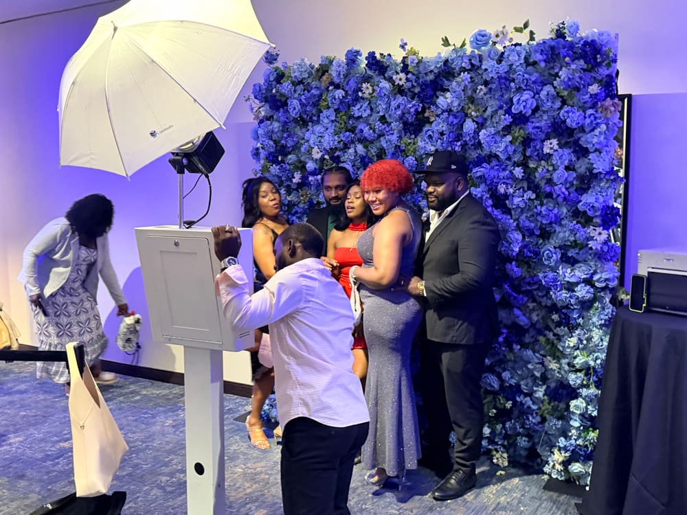 Attendant setting up a group photograph at a blue floral wall