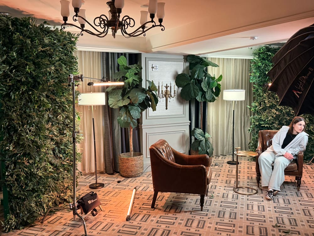 Greenery walls framing a lounge set with leather armchairs for filmed interviews