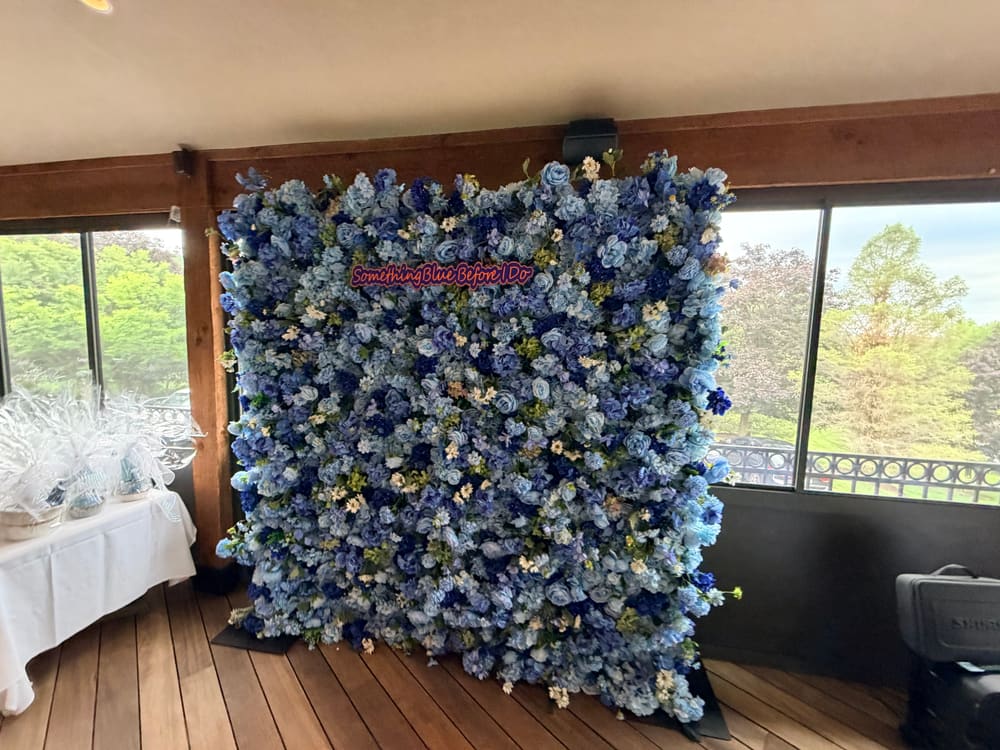 Pale blue floral wall with a Something Blue Before I Do neon sign