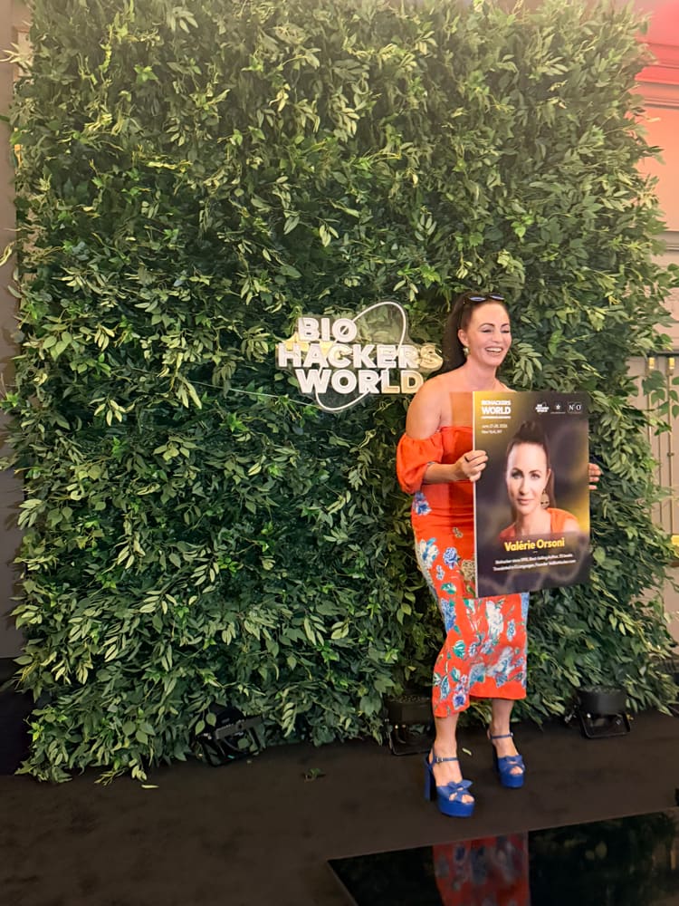 Guest holding a speaker poster in front of a greenery wall