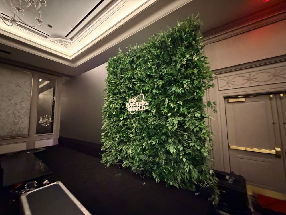 Greenery wall carrying a brand logo in a darkened ballroom