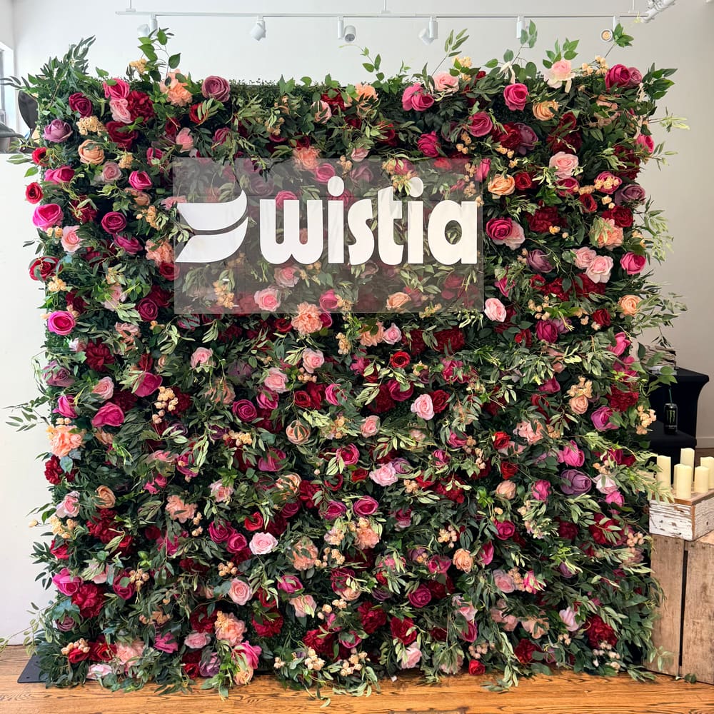 Deep red and pink rose wall with a branded sign at its centre